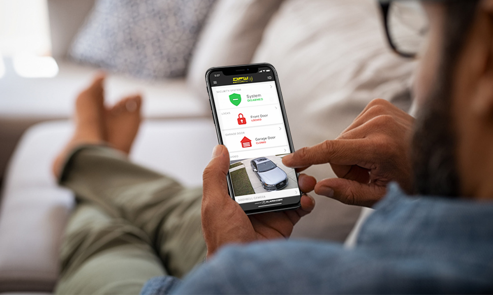 peaceful man on couch looking at DFW security app on his phone