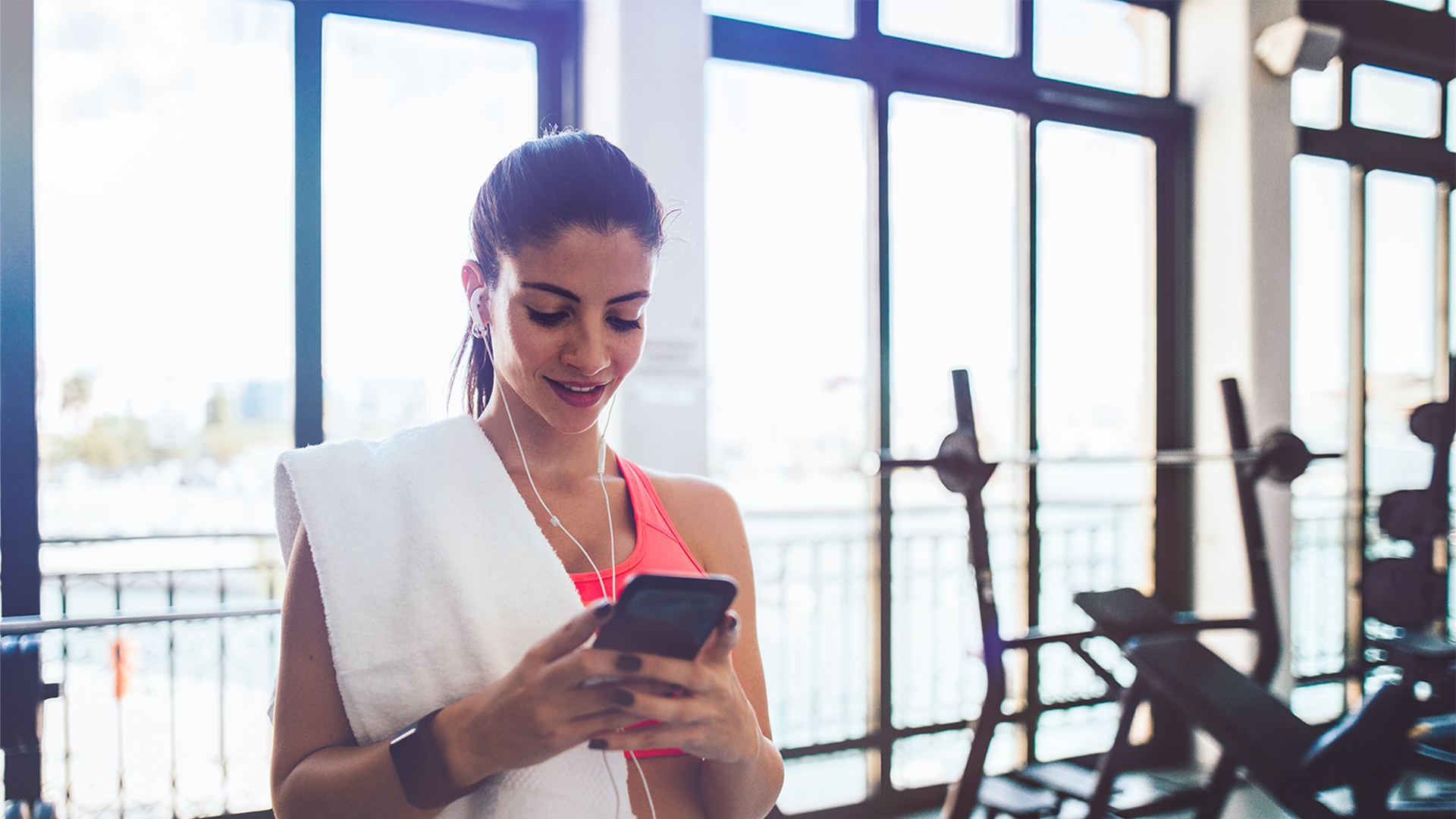 woman checking her home security cameras on her phone at the gym