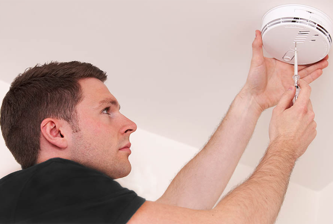 Technician installing smoke detector on ceiling