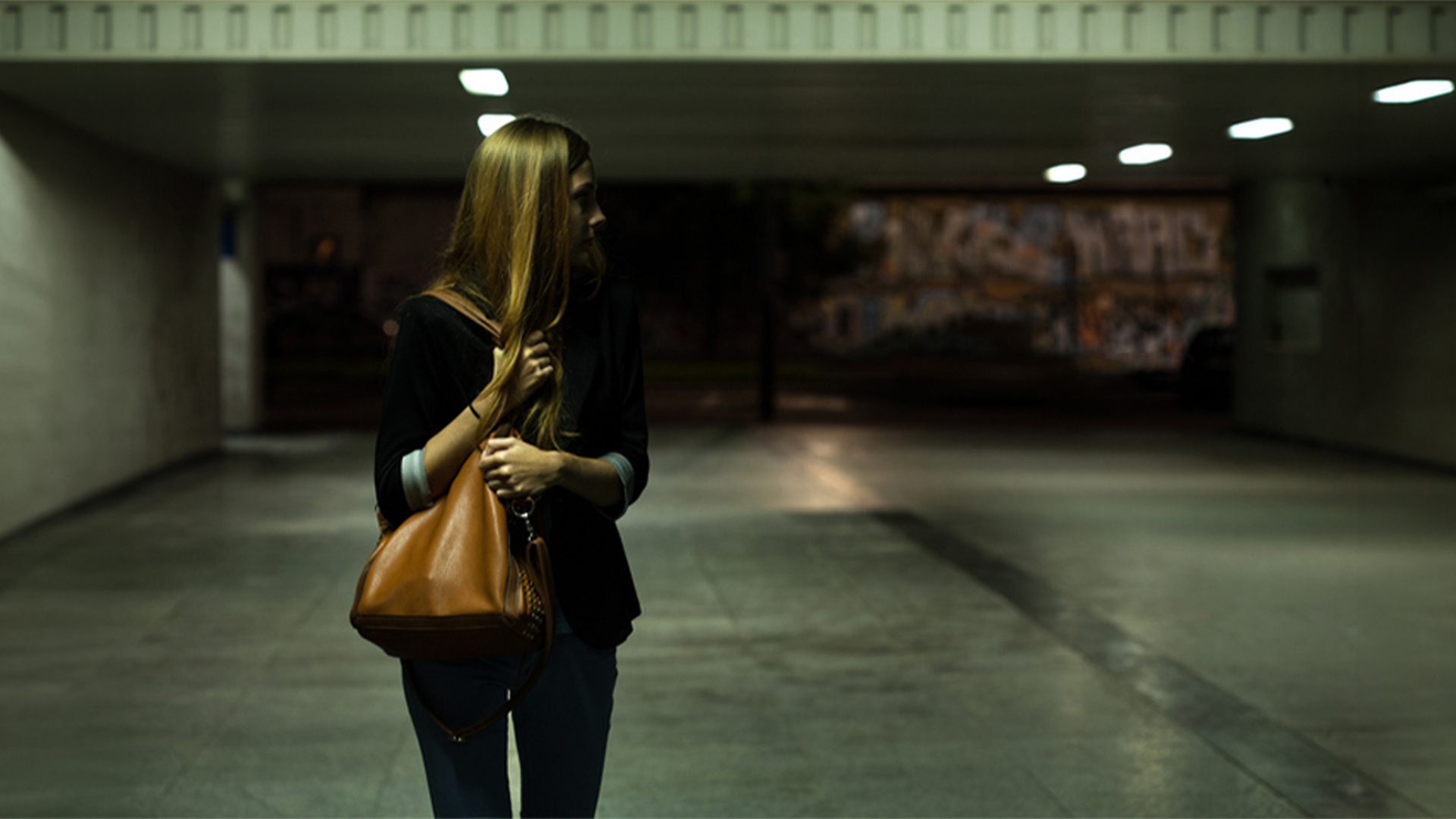 Woman walking alone in parking garage at night