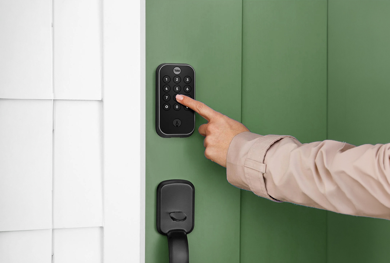 Woman pressing code into smart lock on door