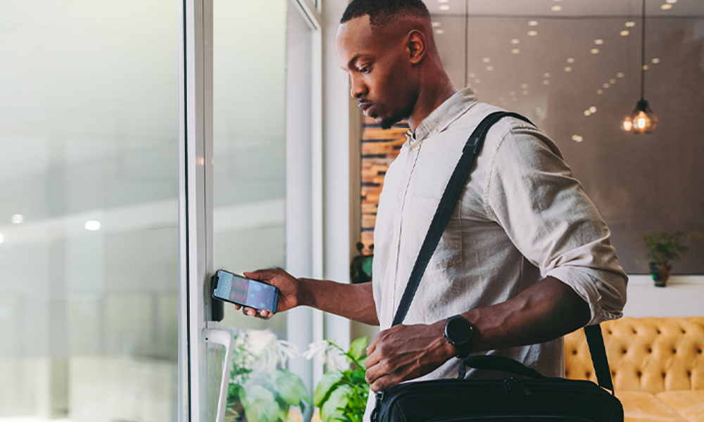 man using phone to unlock door in office