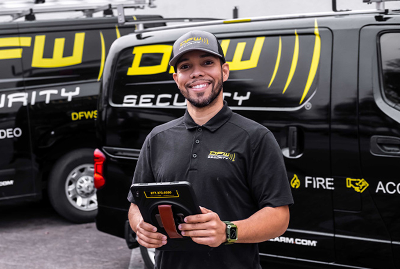DFW Security Technician in front of service vans