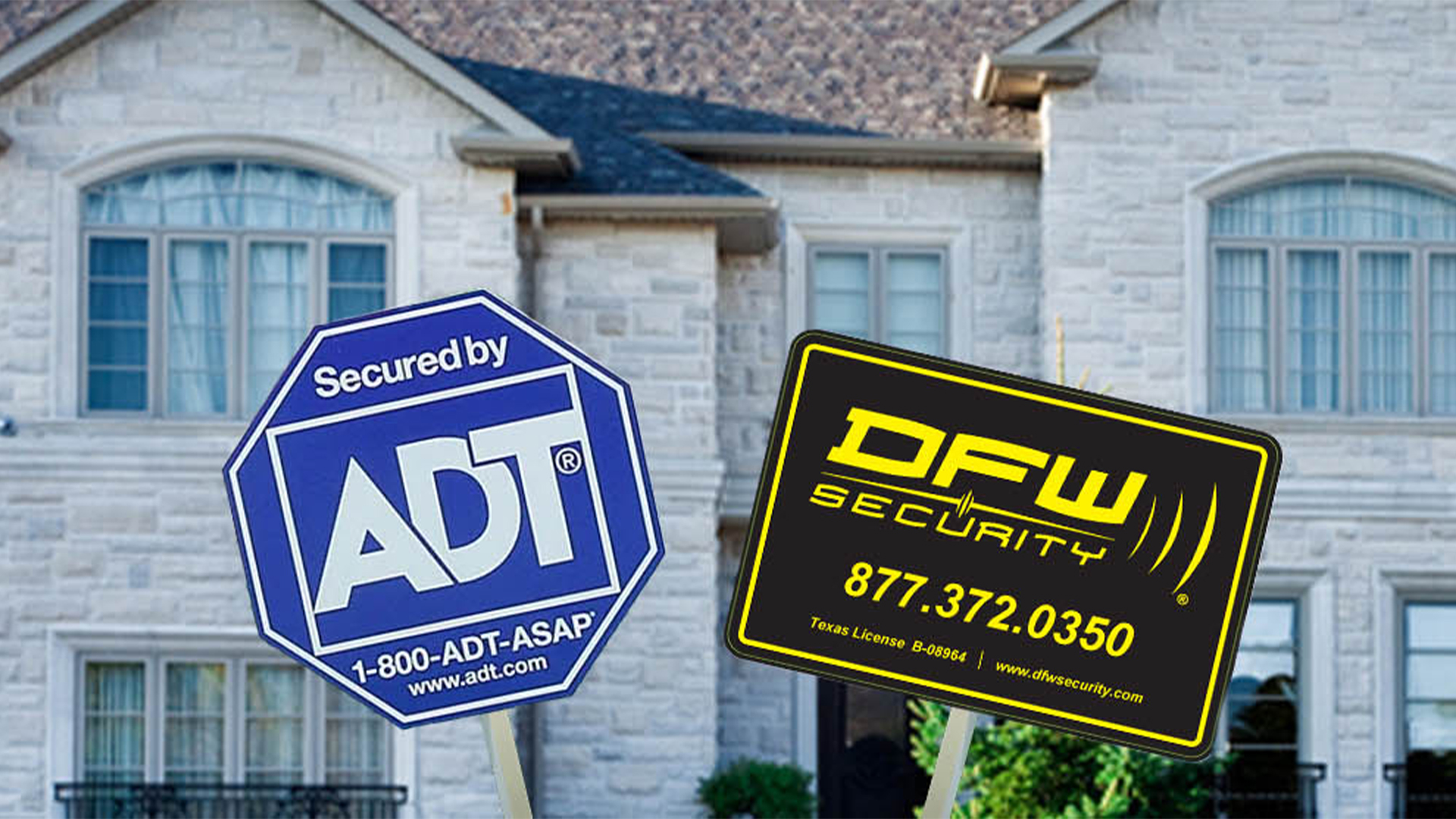 Closeup of ADT and DFW Security yard signs in front of house