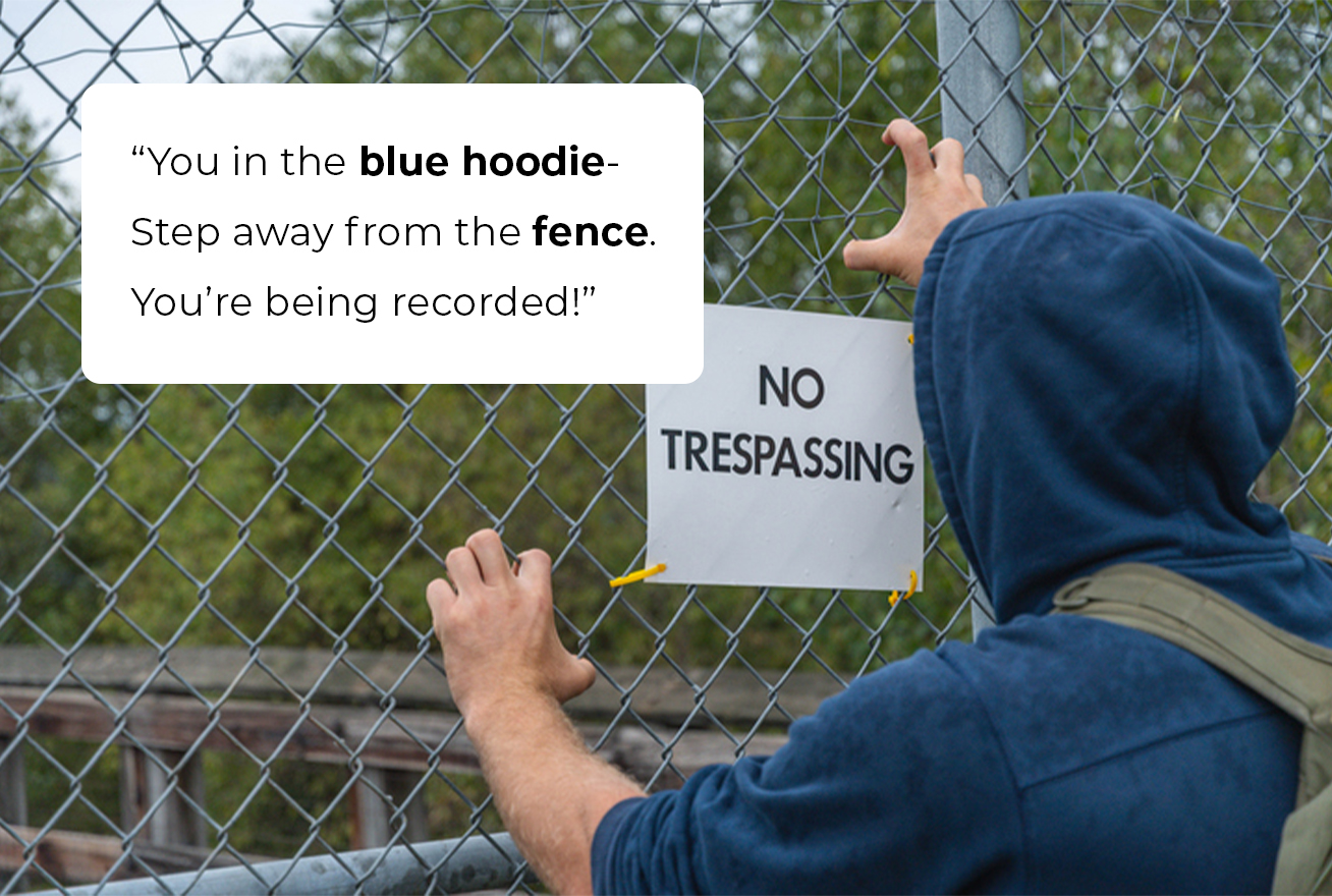 Man about to climb fence with no trespassing sign being warned by camera