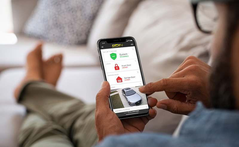 Man controlling his smart home security system on the couch