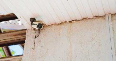 Old broken home security camera outside house