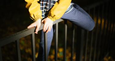 Person climbing a fence into a back yard at night
